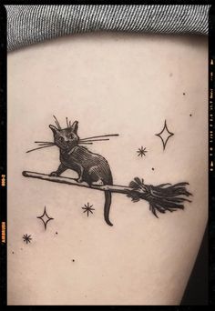 a black and white image of a cat on a broom tattoo design with stars in the background