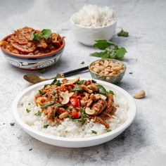 a white bowl filled with rice and meat next to bowls of food on the table