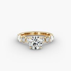 a yellow gold engagement ring with three stones on the band and a round center stone