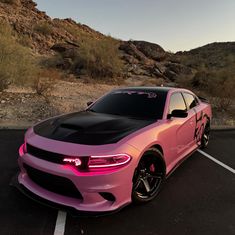 a pink and black car parked in a parking lot