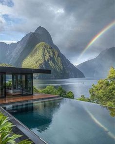 a large pool with a rainbow in the sky above it and mountains behind it,