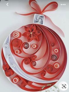 an ornament made out of red and white paper with a bow on top