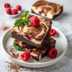 three pieces of chocolate dessert on a plate with raspberries and mint sprigs