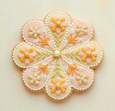 a decorated cookie with yellow and pink flowers on it's side, sitting on a white surface