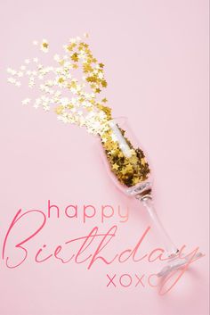 a champagne glass filled with confetti and sprinkles on a pink background