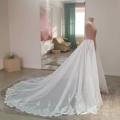 a white wedding dress on display in front of a mirror with the back of it's veil pulled up