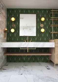 a bathroom with marble counter tops and green wallpaper, along with two gold - toned lights