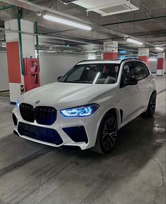 a white bmw suv parked in a parking garage