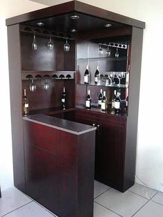 a bar with wine glasses and bottles on the top shelf in a room that has white tile flooring