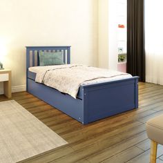 a blue bed sitting on top of a hard wood floor next to a white wall