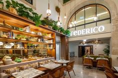 the inside of a restaurant with tables, chairs and shelves full of food on display