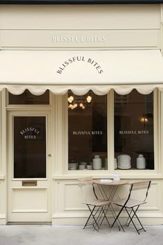 the outside of a restaurant with white awnings and tables in front of it