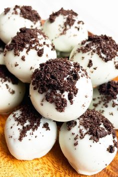 chocolate covered donuts with white frosting and sprinkles on a wooden platter