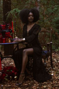 a woman sitting at a table in the woods with an afro hairdow on her head