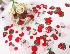 strawberries and strawberry shapes are scattered on the floor next to a vase with flowers