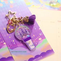 a cell phone charm is laying on top of a purple brochure with stars