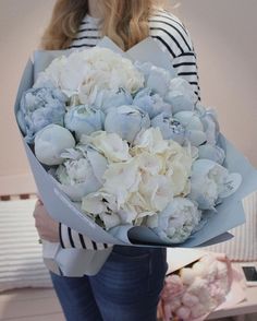 a woman holding a bouquet of white and blue flowers