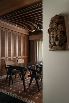 a dining room table with chairs and a large head hanging on the wall above it