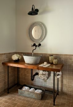 a bathroom sink sitting under a mirror next to a wooden table with shoes on it