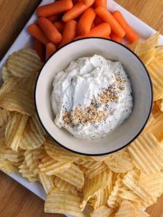 a bowl of dip surrounded by chips and carrots