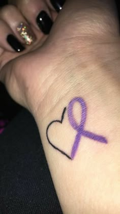 a woman's wrist with a purple ribbon in the shape of a heart