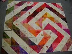 a colorful quilt is laying on the ground next to a piece of paper that has been cut into squares