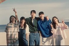 a group of young people standing next to each other on top of a sandy beach