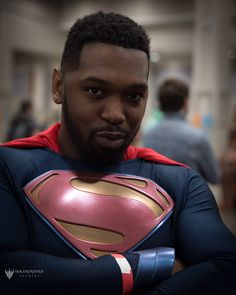 a man in a superman costume standing with his arms crossed