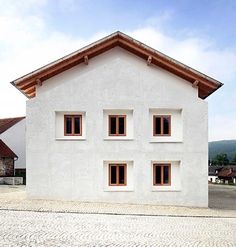 a large white house with windows on the side and brick walkway in front of it