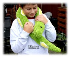 a young boy is holding a green stuffed animal that looks like a crocodile's tail