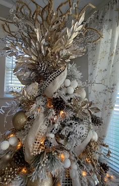 a christmas tree decorated with silver and gold ornaments, pineconi balls and lights