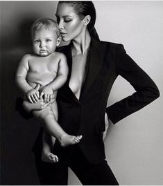 a woman holding a baby in her lap while posing for a black and white photo