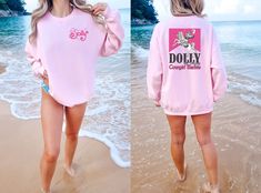 two women in pink sweatshirts walking on the beach with their feet in the water