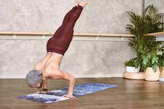 a person doing a handstand on a yoga mat in front of a plant