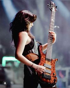 a woman holding a bass guitar on stage