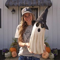 a woman holding a fake ghost and a pumpkin