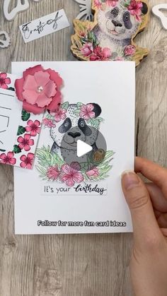 someone holding up a card with a panda bear on it and flowers around the edges