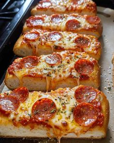 several slices of pepperoni pizza are lined up on a baking sheet