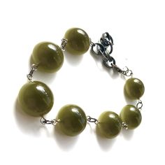 Olive green in a rich deep tone & subtle moonglow in the shape of rounded flat backs, meet gritty gun metal chain in this adjustable to 8.5" Stations Bracelet. Enough of a statement to be worn on it's own OR stack for an arm party with others. Lots of versatility from 6.5 to 8.5" and swivel lobster claw makes it so that you can latch a link all by yourself. Light weight with a chunky look. Because the beads we use are vintage & sometimes very limited, beads may vary slightly from the des Green Bracelet With Adjustable Chain, Green Bracelets With Adjustable Chain, Adjustable Green Metal Bracelets, Surgical Steel Earrings, Arm Party, Rainbow High, Moon Glow, Vintage Lucite, Arm Candy