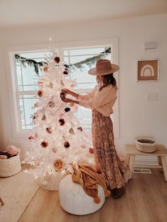 a woman decorating a white christmas tree