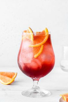 a red drink with orange slices on the rim