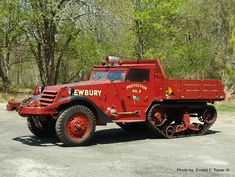 an old red tow truck parked in front of some trees