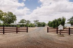 a dirt road that has a fence in front of it