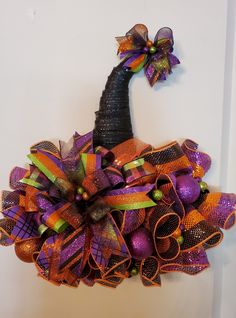 a purple and orange mesh wreath hanging on the wall with a black hat attached to it