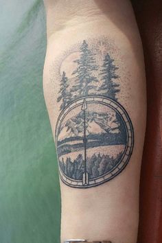 a person with a tattoo on their arm that has trees and mountains in the background