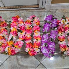 three vases filled with colorful flowers sitting on top of a tile floor next to a door