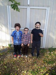 three young boys with fake mustaches standing in front of a white wall and fence