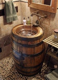 a wooden barrel sink in a bathroom next to a mirror