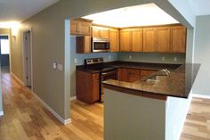 an empty kitchen with wood floors and stainless steel appliances