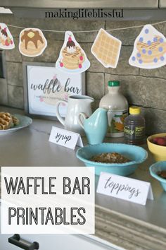 a counter topped with plates and bowls filled with food next to a sign that says waffle bar printables